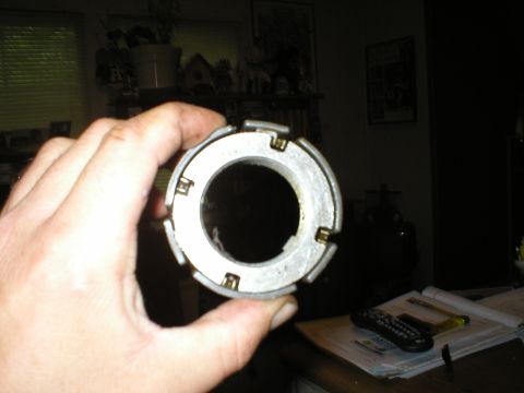 1986 Ford Bronco - A hand holds a metal circular part with several clips around its circumference.