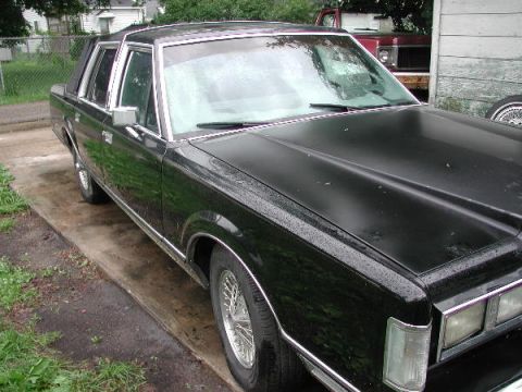 1987 Lincoln Town Car - A black 1987 Lincoln Town Car is parked on a driveway, with another vehicle visible in the background.