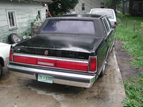 1987 Lincoln Town Car - Rear view of a black 1987 Lincoln Town Car parked next to a white van.
