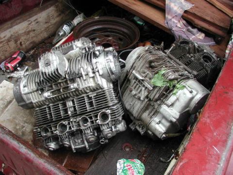 1987 Lincoln Town Car - Several motorcycle engines are piled in the bed of a truck, along with other discarded items.