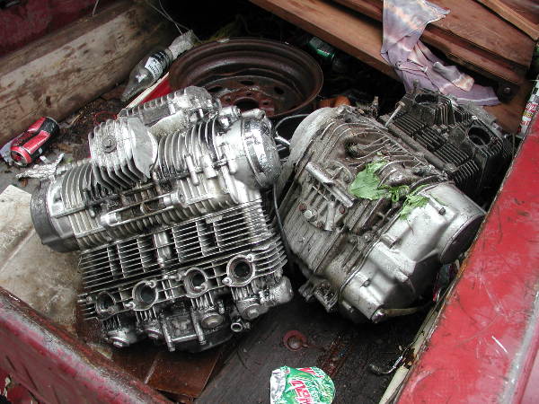 Two used air-cooled inline-four motorcycle engines in a rusty red truck bed