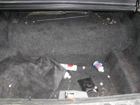 1987 Lincoln Town Car - The interior of a car trunk shows a spare tire, a cleaning product, and scattered debris.