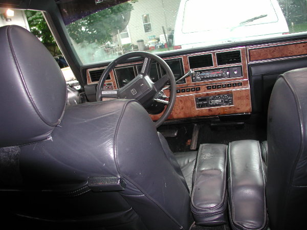 Interior view of a car with leather seats, wood trim dashboard, and a steering wheel