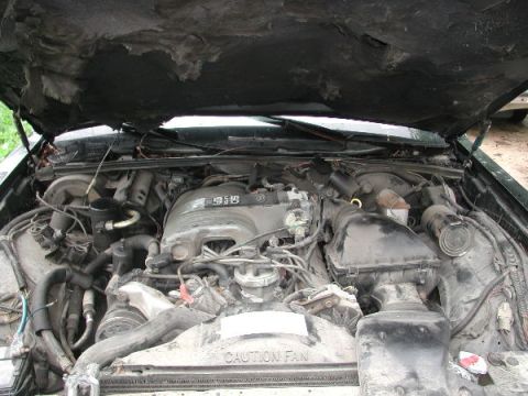 1987 Lincoln Town Car - The engine bay of a 1987 Lincoln Town Car, its V8 engine and visible caution fan warning.