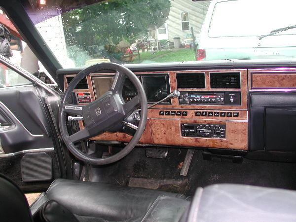 1980s luxury sedan dash with woodgrain trim, digital cluster and stereo