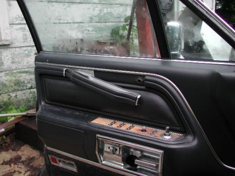 1987 Lincoln Town Car - Close-up view of a car's interior door panel with various controls and trim details.