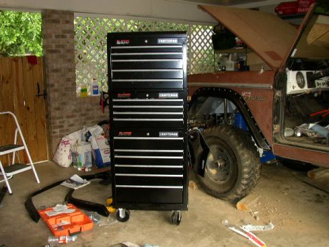 1995 Ford Bronco - A large black toolbox sits beside a vintage SUV undergoing repairs in a garage setting.