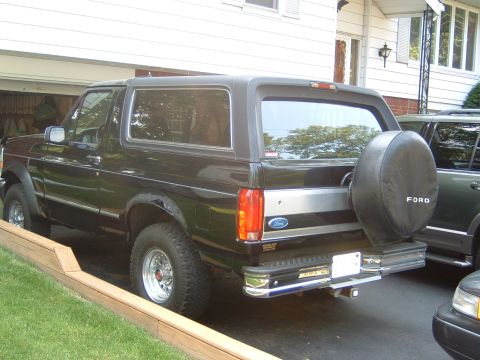 1993 Ford Bronco - Rear view of a black Ford Bronco with a silver stripe and a spare tire cover.