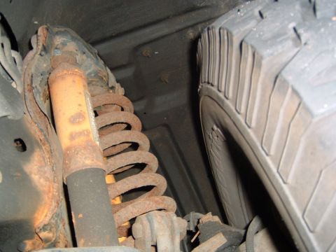 1993 Ford Bronco - Close-up view of the undercarriage, showing a rusty suspension component and a tire.