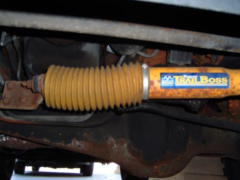 1993 Ford Bronco - Underside view of a vehicle's steering stabilizer with a yellow bellows and a 'Super Trail Boss' sticker.