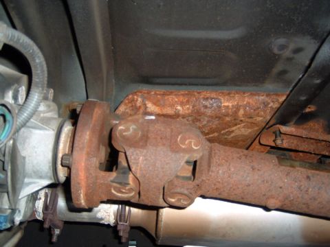 1993 Ford Bronco - Underside view of a rusty driveshaft and differential assembly, showing significant corrosion.