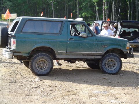 1993 Ford Bronco - Side view of a green 1993 Ford Bronco with a spare tire mounted on the rear door.