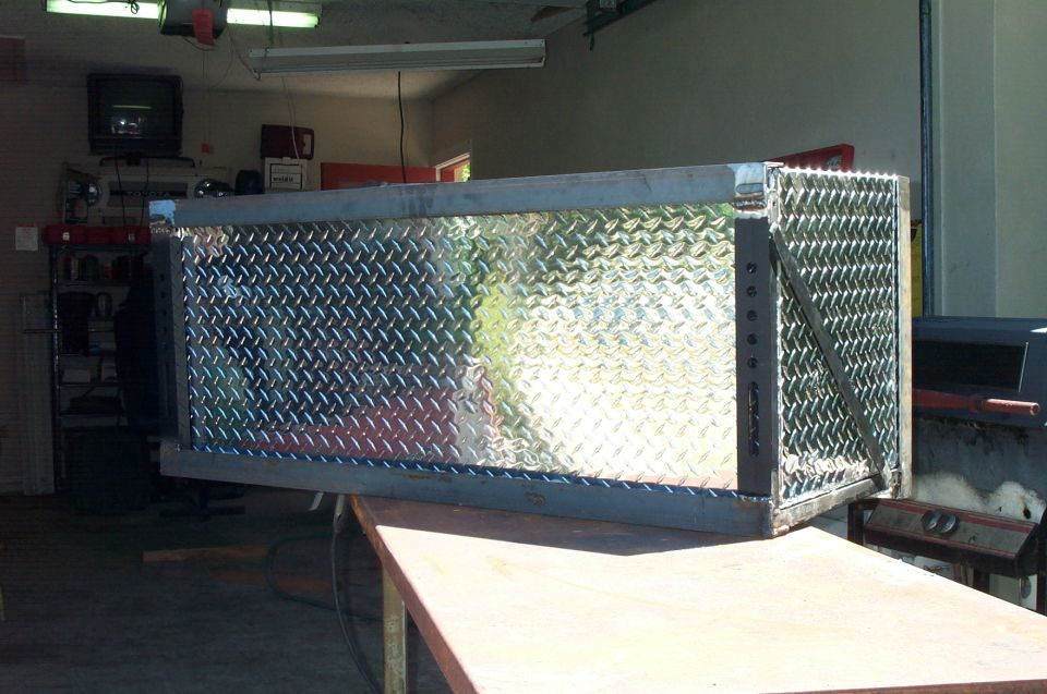 Welded bare-steel bracket frame around a diamond-plate toolbox on a shop bench