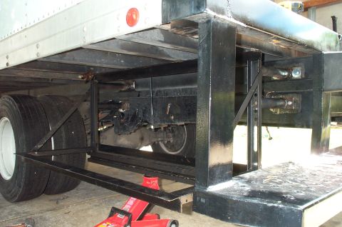 1995 Ford Bronco - Low rear-corner view of a flatbed truck showing a fresh black-painted steel subframe, bumper support gussets and rear underride structure b…