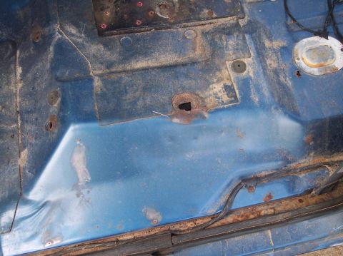 1990 Ford Bronco - The interior floor pan shows significant rust damage and holes, indicating extensive body work is needed.