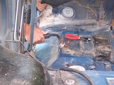 1990 Ford Bronco - Welding is being performed on the interior floor of a vehicle, with tools nearby.