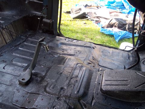1990 Ford Bronco - Vehicle interior floor with undercoating applied, brake pedal visible.