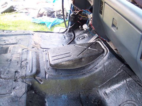 1990 Ford Bronco - Interior floor of a gutted truck or SUV cab shot from the passenger side, showing the stamped transmission tunnel and floor pan freshly coa…