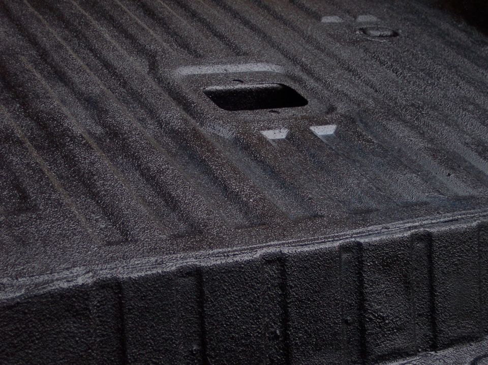 Black textured truck bedliner with ribbed surface and rectangular cutout