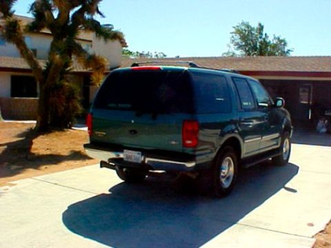 1997 Ford Expedition - The rear of a dark green SUV is visible in a residential driveway under a clear blue sky.