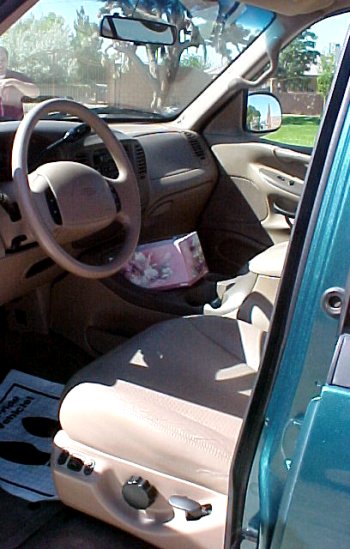 1997 Ford Expedition - The interior of a 1997 Ford Expedition shows tan seats and dashboard with a teal exterior door panel on the door.