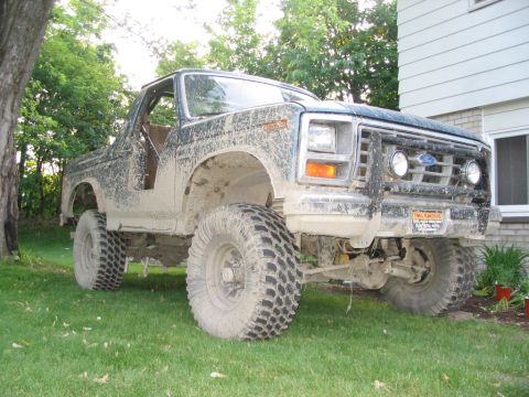 1986 Ford Bronco - This heavily modified Ford Bronco is covered in mud, suggesting recent off-road use.