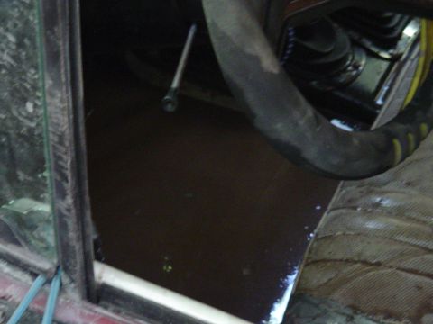 1993 Ford Bronco - The interior of a vehicle is visible, with a dark floor and a large hose obscuring the view.