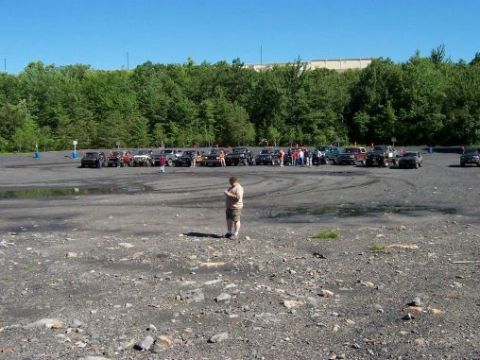 1996 Ford Bronco - A gathering of SUVs and trucks are parked in an outdoor lot under a clear blue sky.