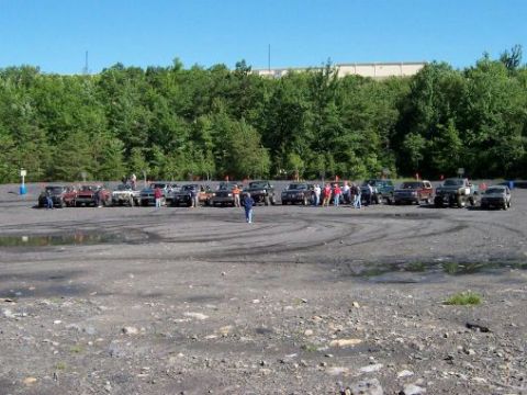 1996 Ford Bronco - A gathering of SUVs and trucks are parked in an open lot.