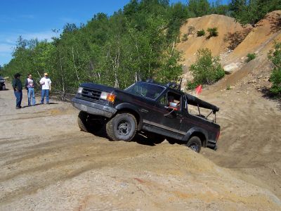 1996 Ford Bronco - A black Ford Bronco navigates an off-road course with a steep incline.