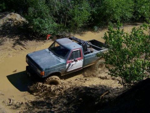 1996 Ford Bronco - This pickup truck navigates a muddy trail, kicking up a significant amount of water and dirt.