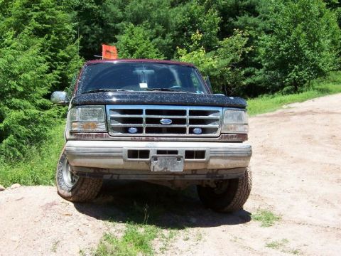 1996 Ford Bronco - This 1996 Ford Bronco is seen from the front, parked on a dirt road with trees in the background.