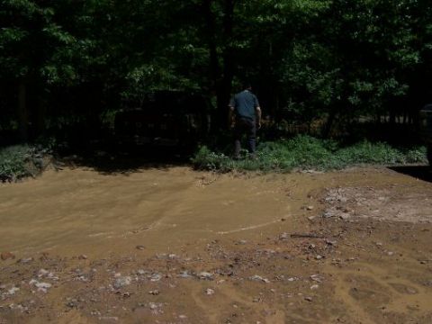 1996 Ford Bronco - A Ford truck is stuck in a muddy area with trees in the background and a person standing nearby.