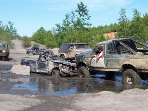 1996 Ford Bronco - Several off-road vehicles are stuck in the mud during an outdoor event.