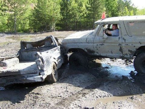 1996 Ford Bronco - Two off-road vehicles are stuck in deep mud, with one appearing to be a total loss.