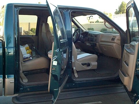 1999 Ford F-250 - The interior of a 1999 Ford F-250 crew cab pickup truck is visible with all doors open, revealing the tan seats and dashboard.