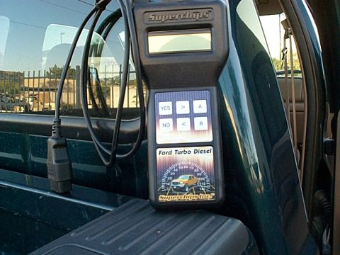 1999 Ford F-250 - A Superchips programmer for Ford Turbo Diesel engines rests on the edge of a dark green pickup truck bed.