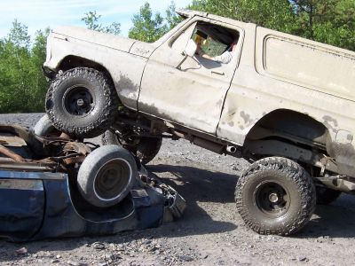 1996 Ford Bronco - A tan SUV is positioned on top of a crushed car, with the SUV's body style suggesting a 1978 model year.