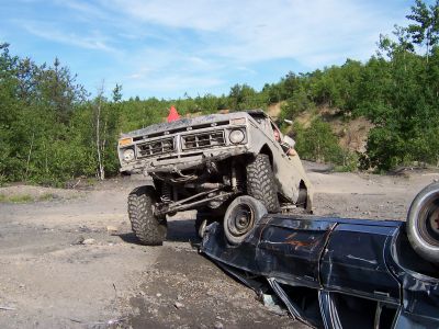 1996 Ford Bronco - Off-road truck on top of another vehicle during an event. The truck appears to be from the 1970s.