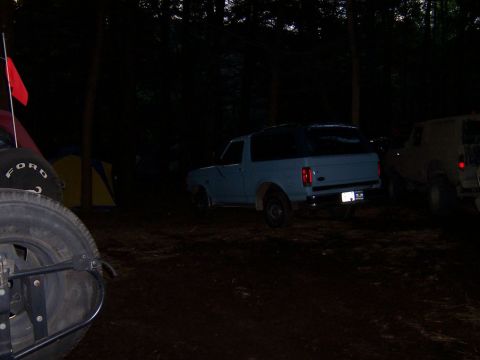 1996 Ford Bronco - Two SUVs are parked in a dark, wooded area at night.