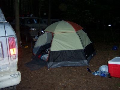 1996 Ford Bronco - A campsite scene at night with a tent, a van, and another vehicle visible.