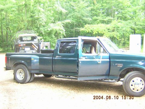 1984 Chevrolet Blazer - A green Ford F-350 dually truck is parked outdoors with its driver's door open, and another vehicle is visible in its bed.