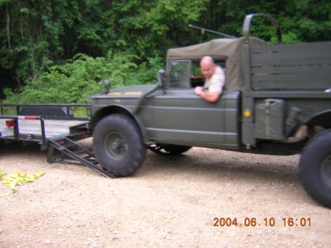 1984 Chevrolet Blazer - A man drives a military truck onto a trailer in a wooded area.