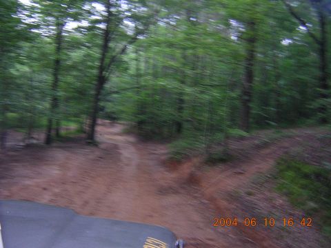 1984 Chevrolet Blazer - A vehicle navigates a dirt trail in a wooded area, captured with significant motion blur.