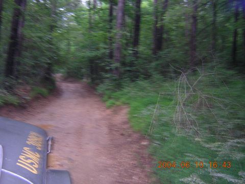 1984 Chevrolet Blazer - Vehicle with USMC 3099 marking drives on a dirt road through a wooded area.