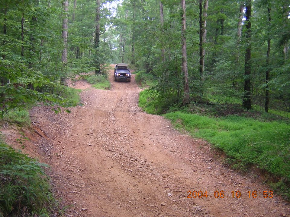 SUV on a dirt road in woods. Date stamp says 2004