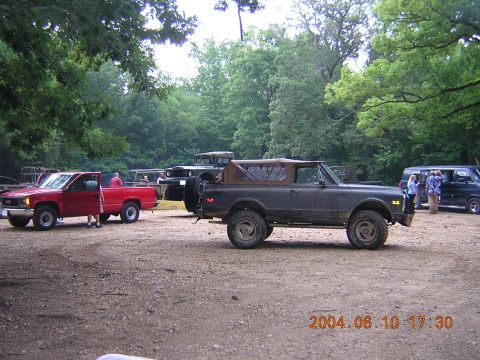 1984 Chevrolet Blazer - Several vehicles are gathered outdoors on a dirt area, with trees in the background.