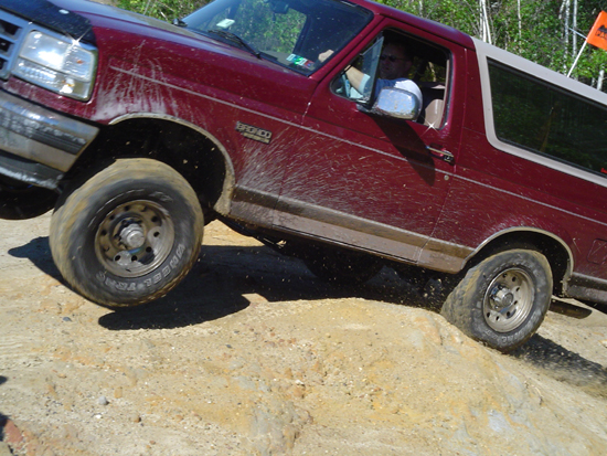 Red 1992 Ford Bronco off-roading, side view