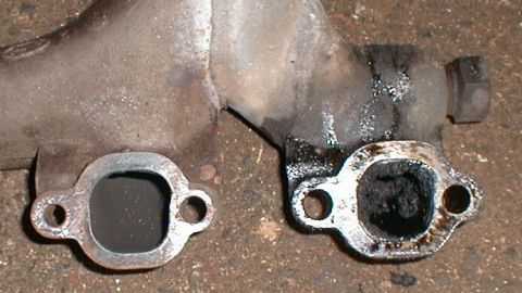 1990 Ford Bronco - Close-up of two exhaust manifold sections, one showing significant carbon buildup.