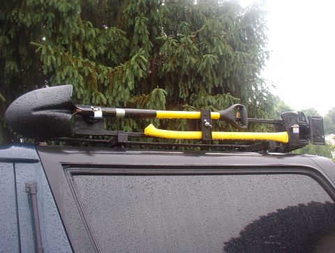1993 Ford Bronco - Tools are mounted on the roof rack of a vehicle, with trees in the background.